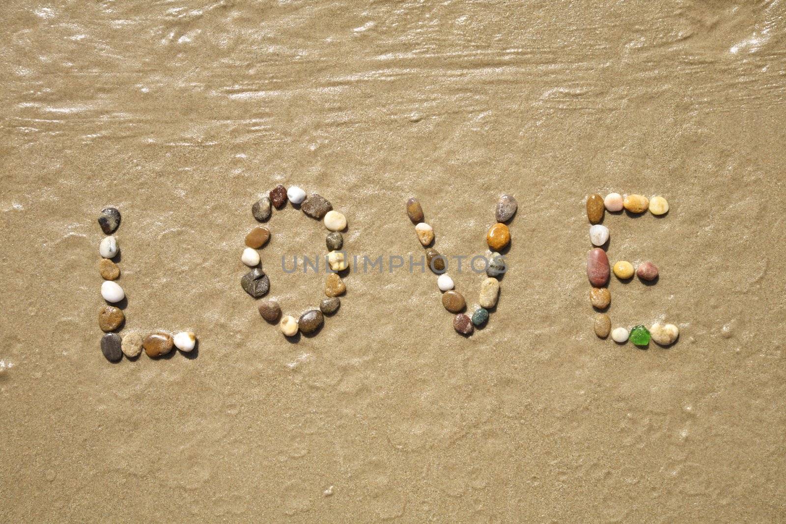 Love word writing with small stones on sand beach ground