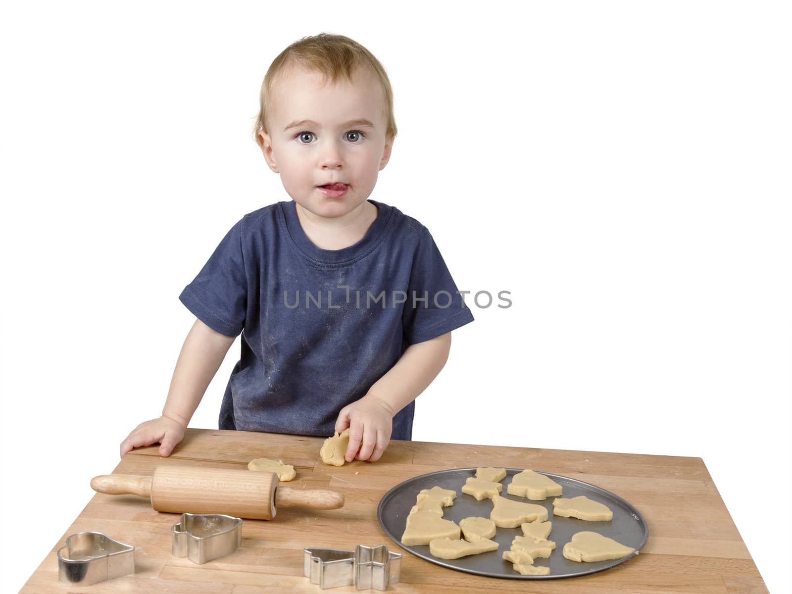 young child making cookies on small wooden desk