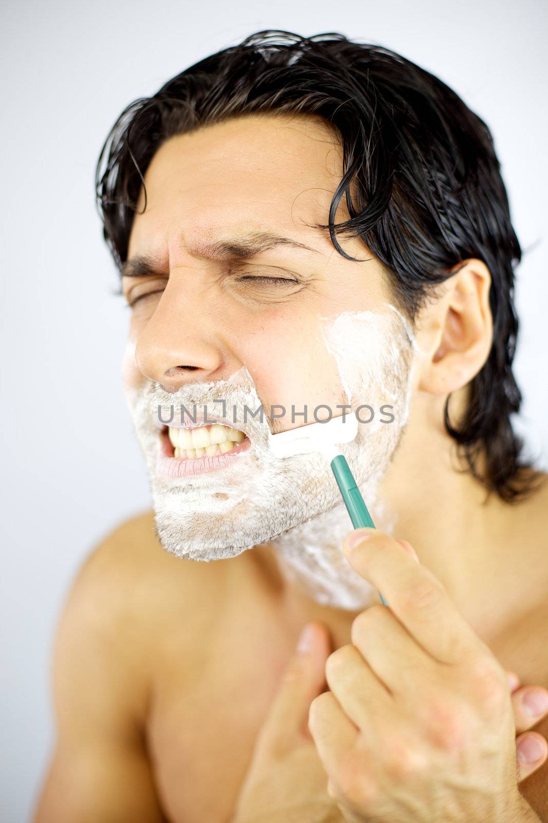Young man hurting himself shaving with blade by fmarsicano