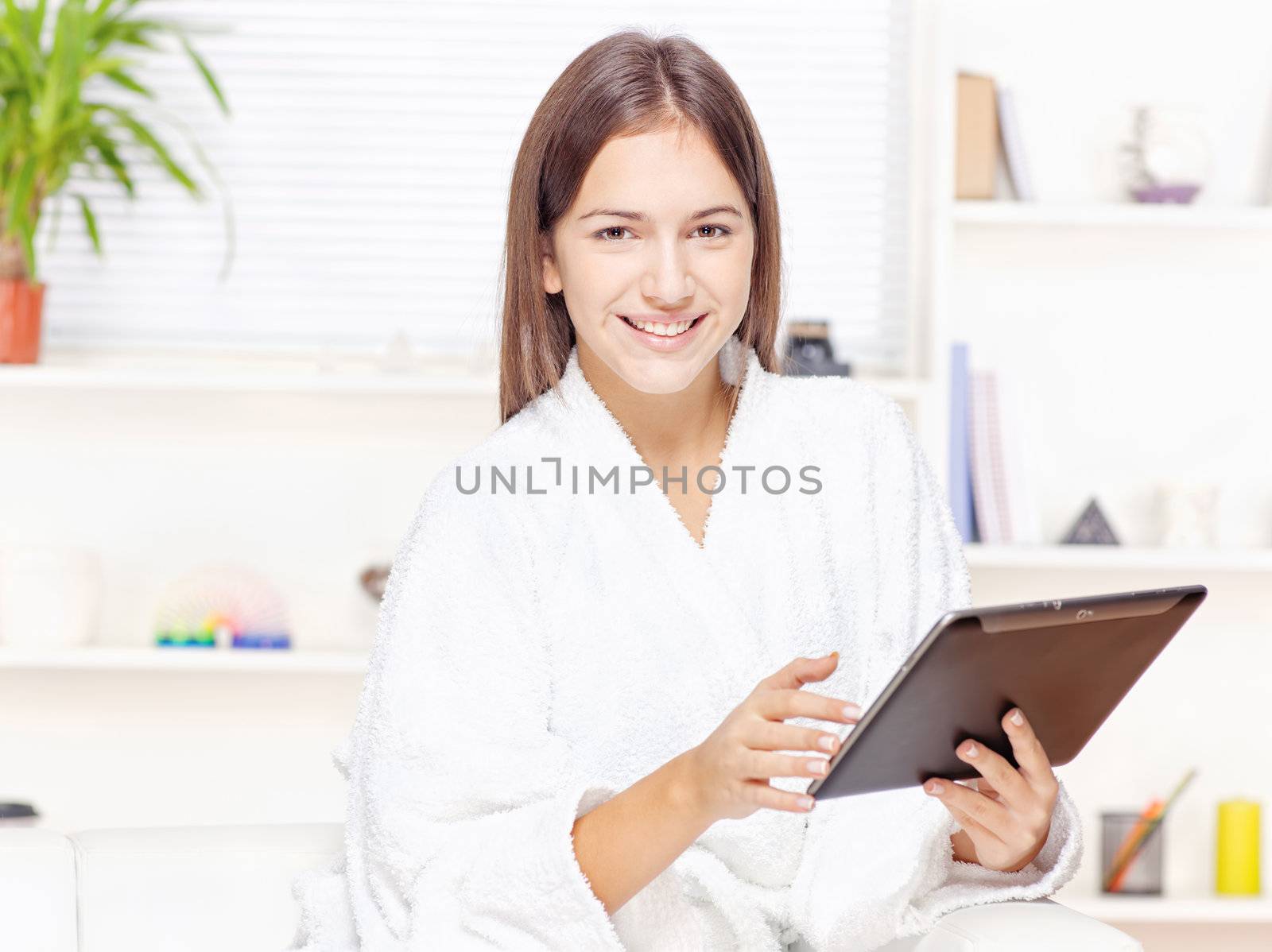 girl in bathrobe at home with touch pad by imarin