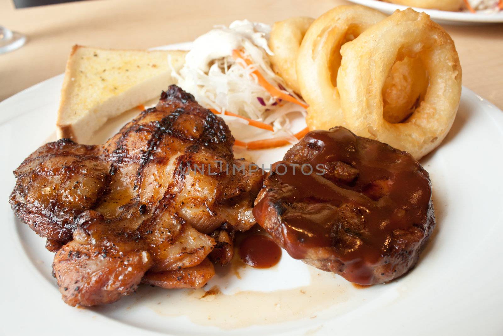 Chicken and pork steak in white plate with salad and fries onion ring