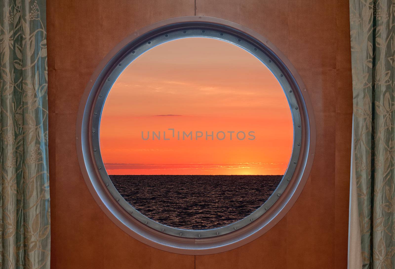 View of a sunrise through the porthole of a cruise ship