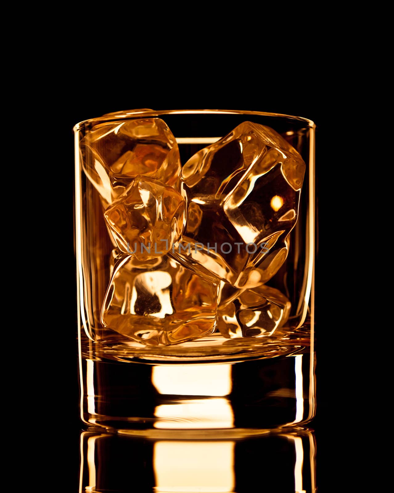 Empty whiskey glass with ice cubes on black background