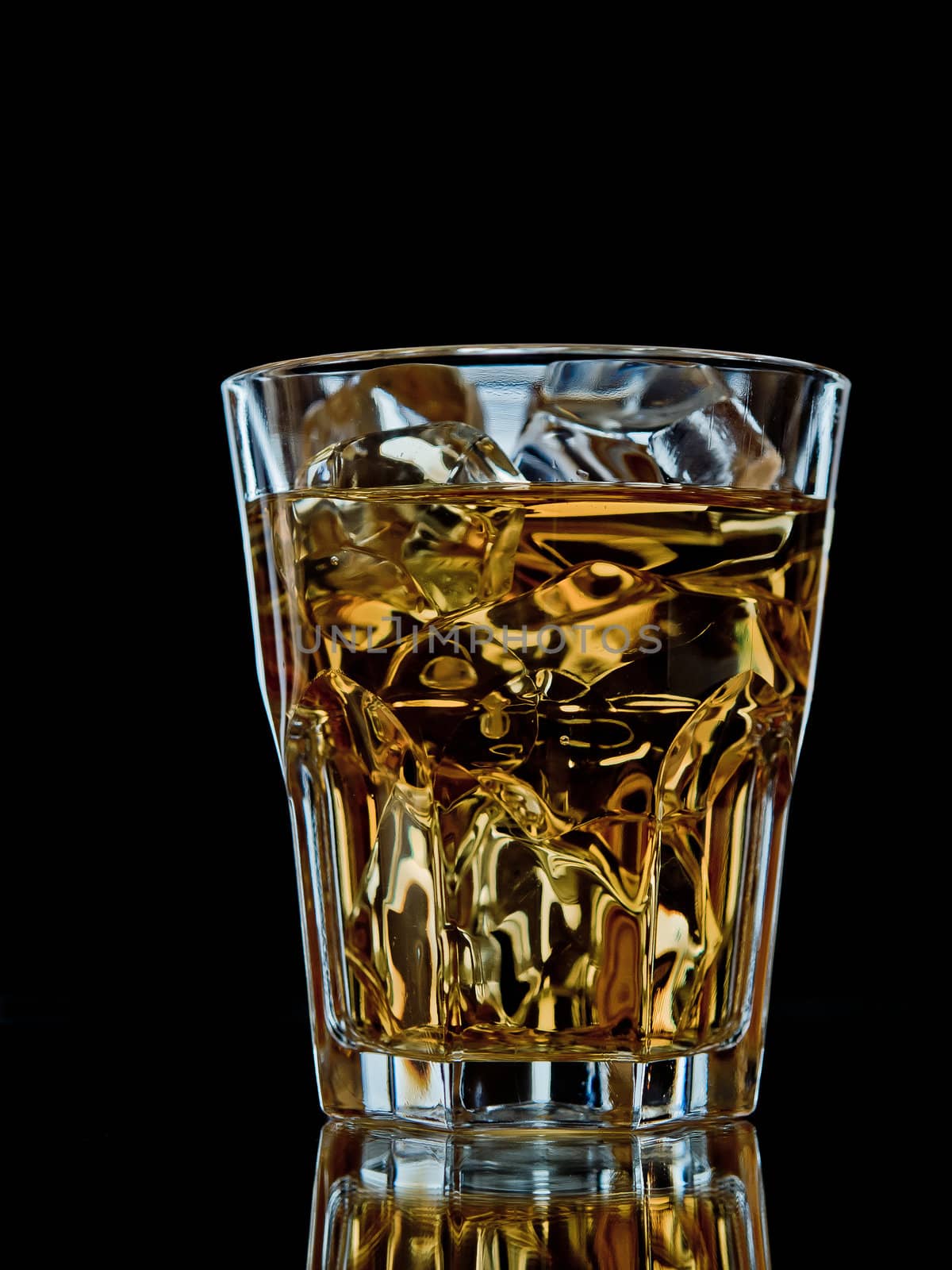 Glass of whiskey on the rocks on black background