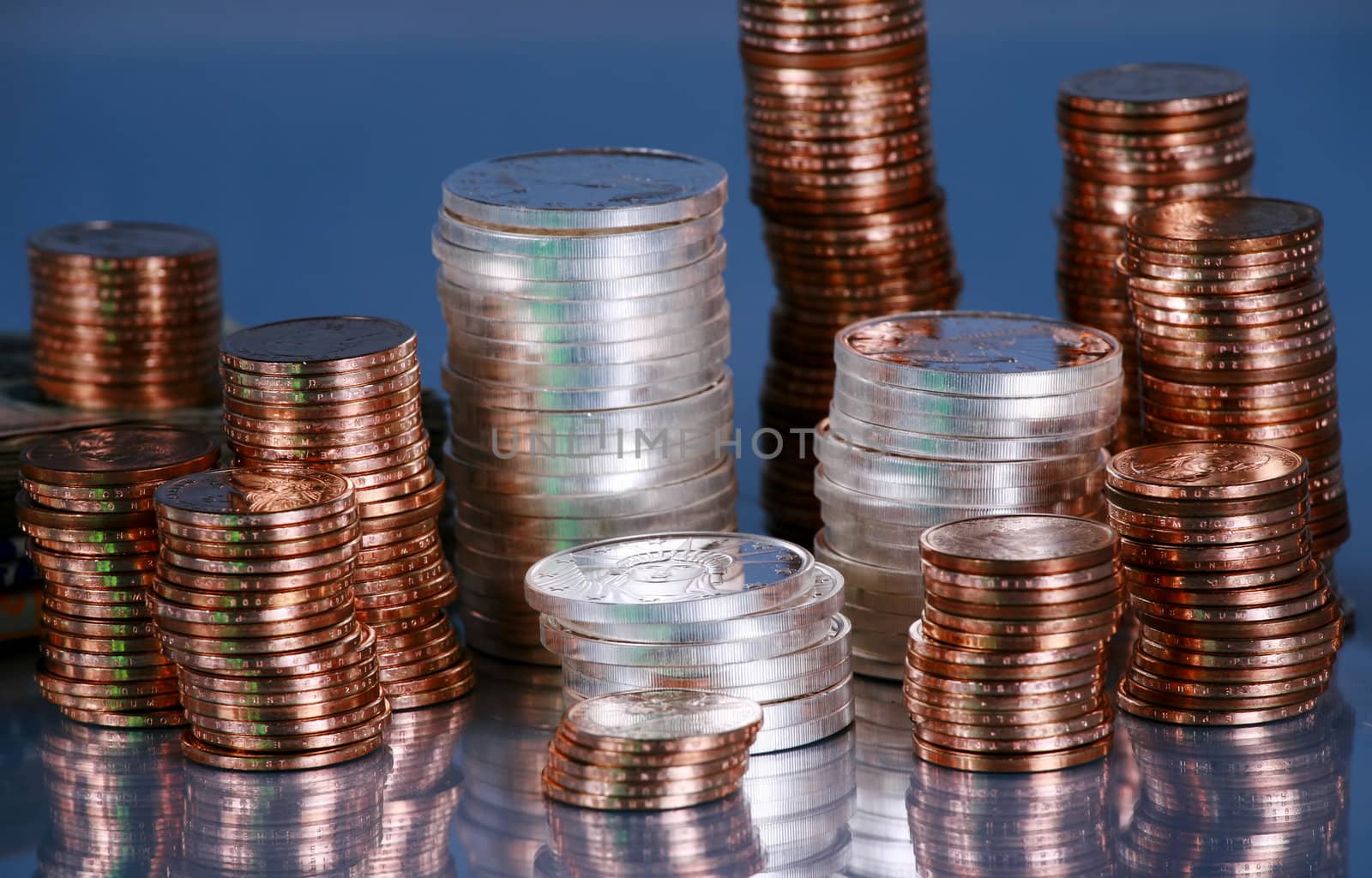 Stacks of silver and gold coins on black reflective surface