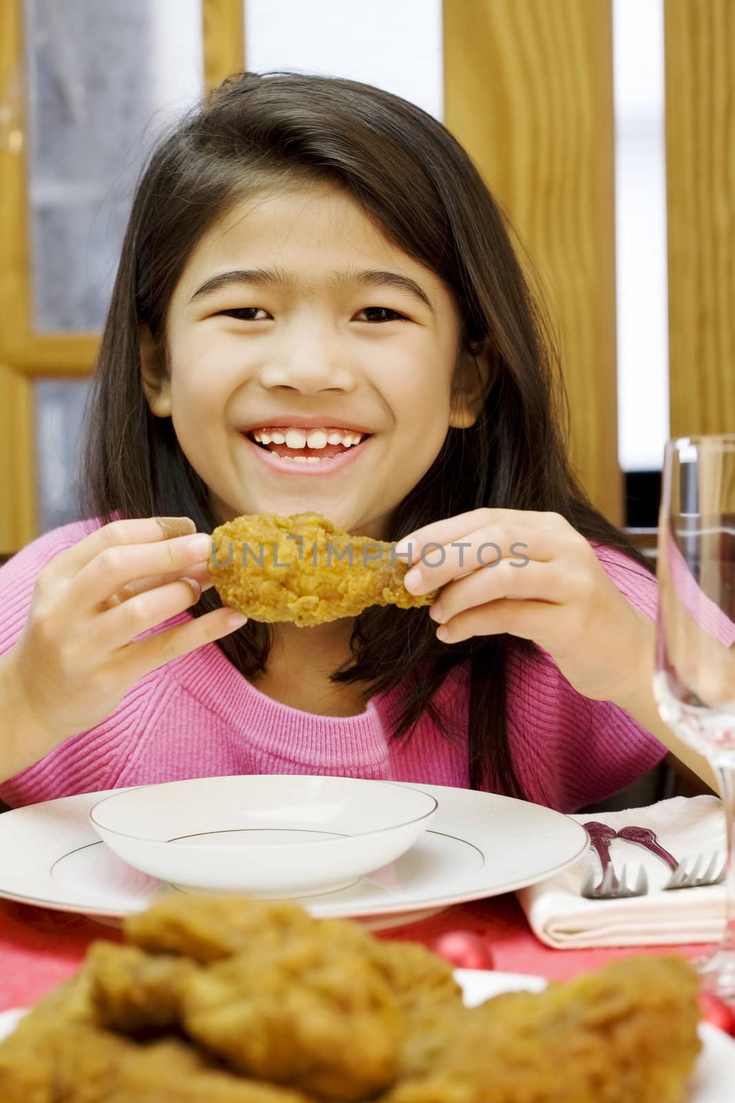 girl eating fried chicken drumstick at dinner
