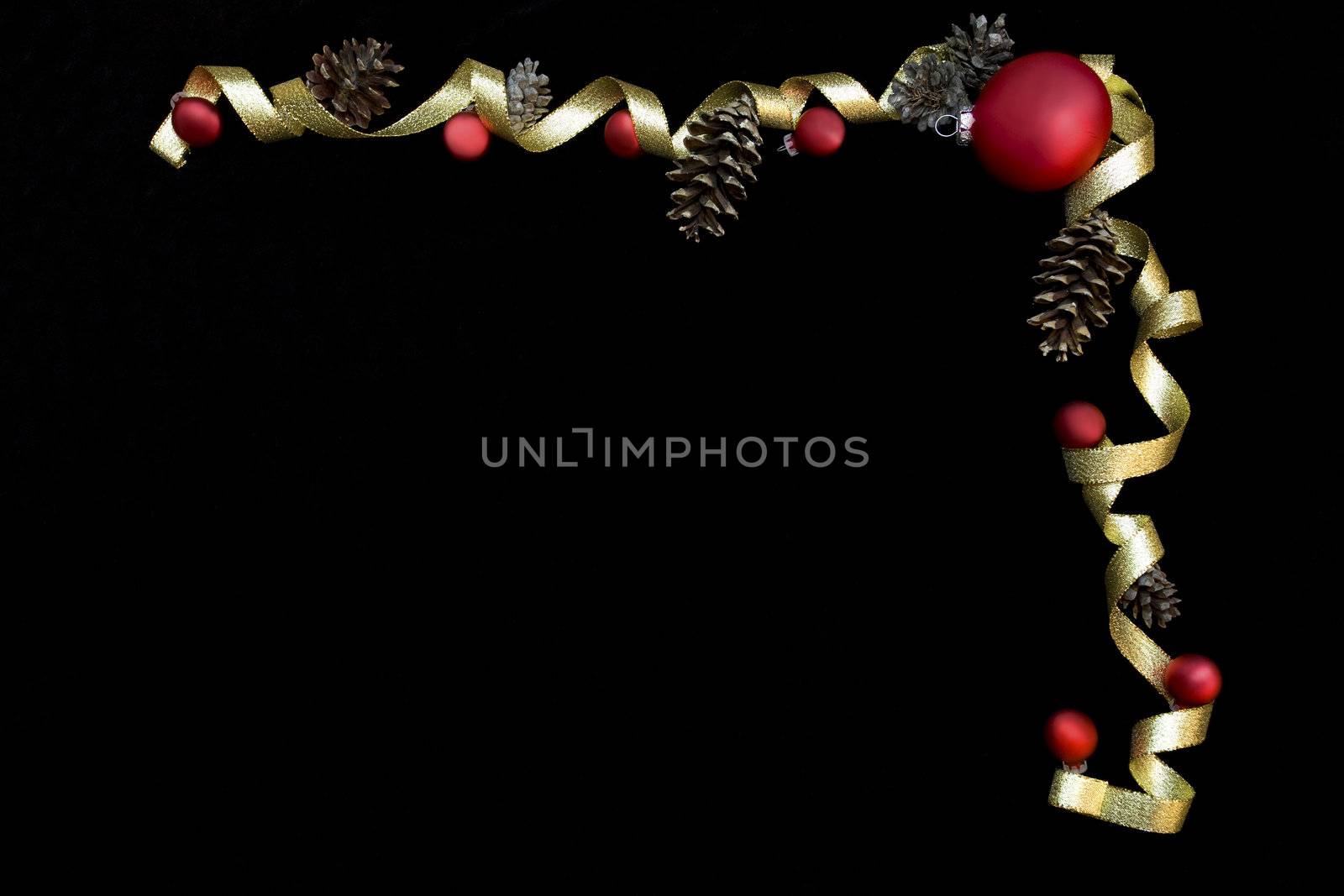 Red ornaments and gold ribbon on black background framing space for text