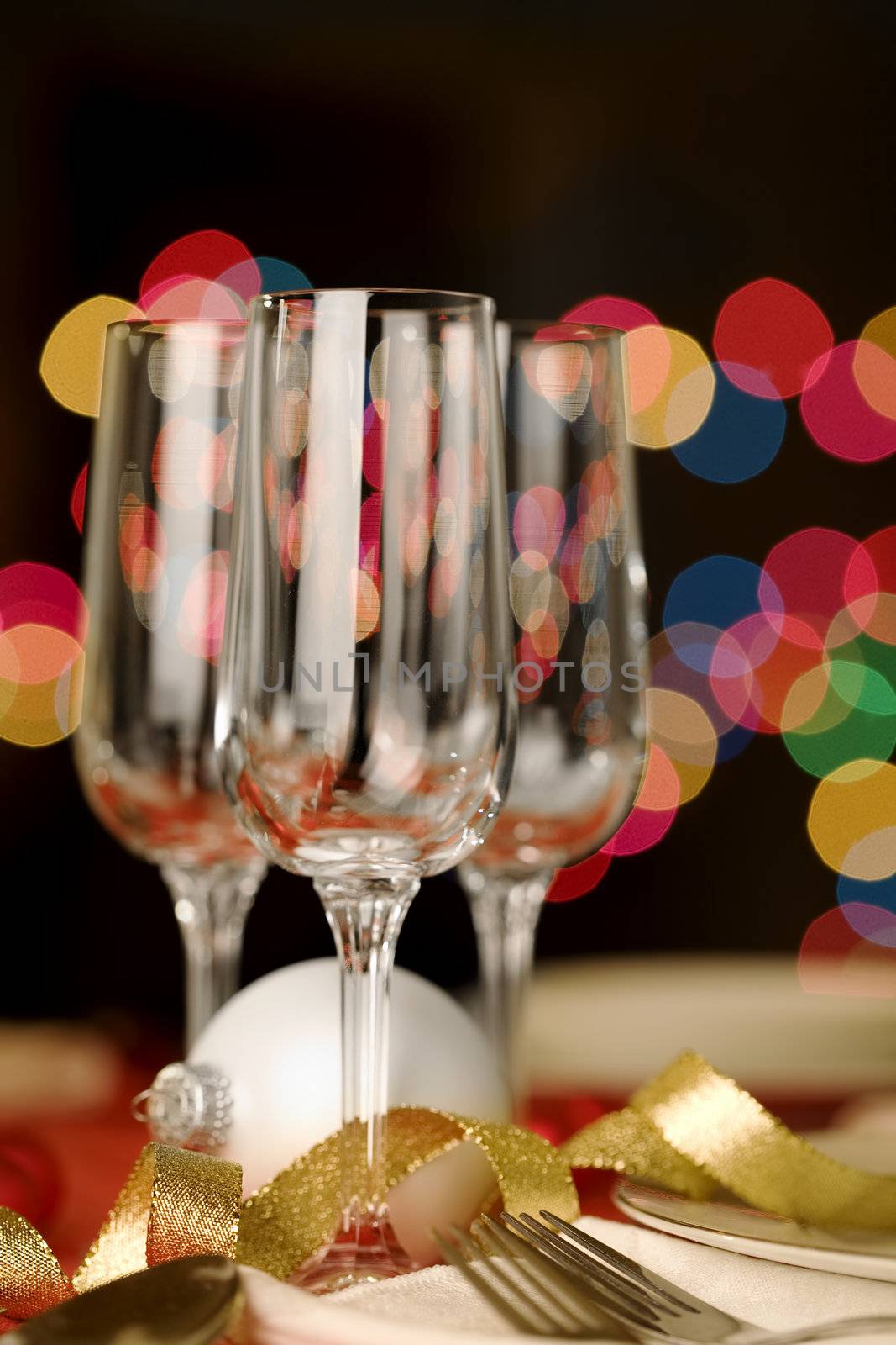 Three empty wine glasses with Christmas theme, colorful lights in background
