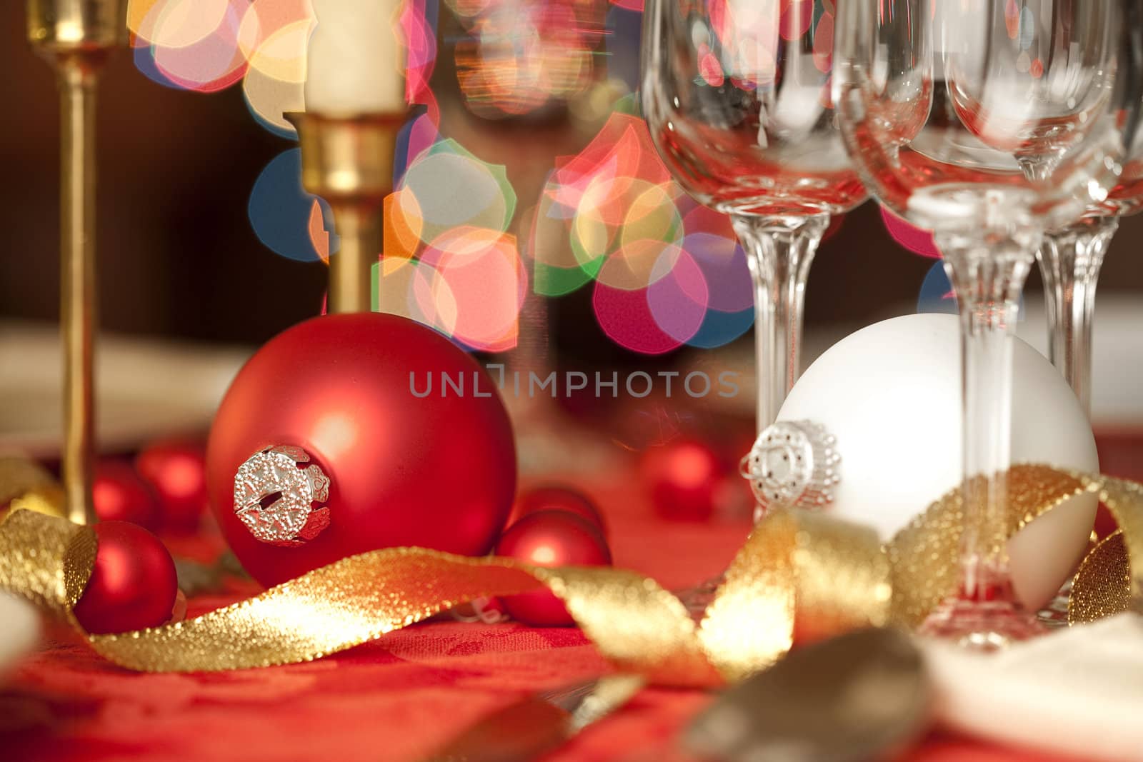 Red and white Christmas ornaments as table decorations, amidst wine glasses