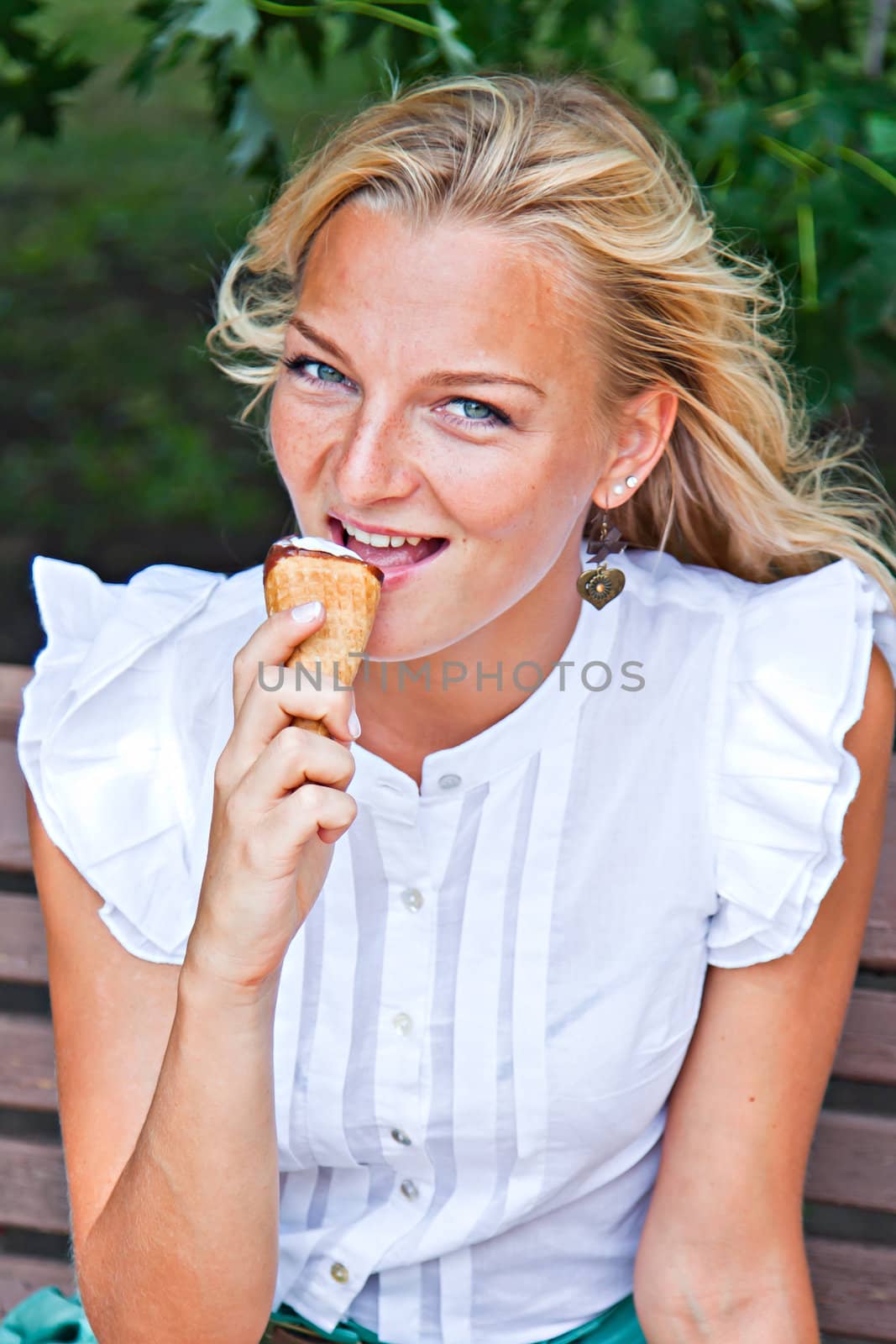 Young and beautiful woman eating ice cream in park