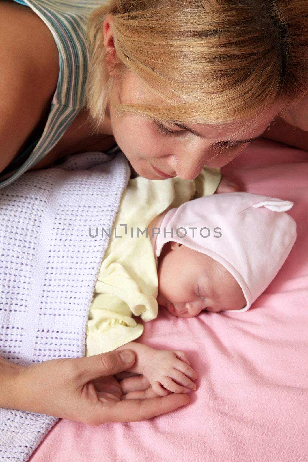 Mother with her sleeping newborn baby in home