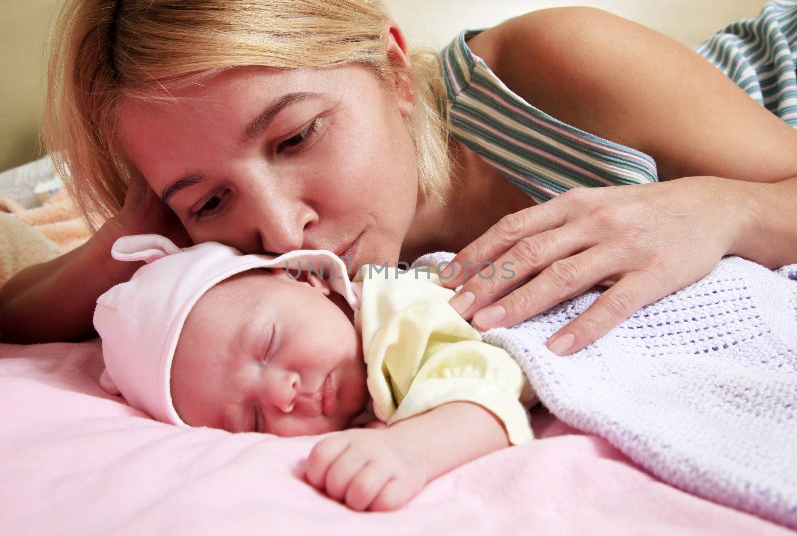 Mother with her sleeping newborn baby in home