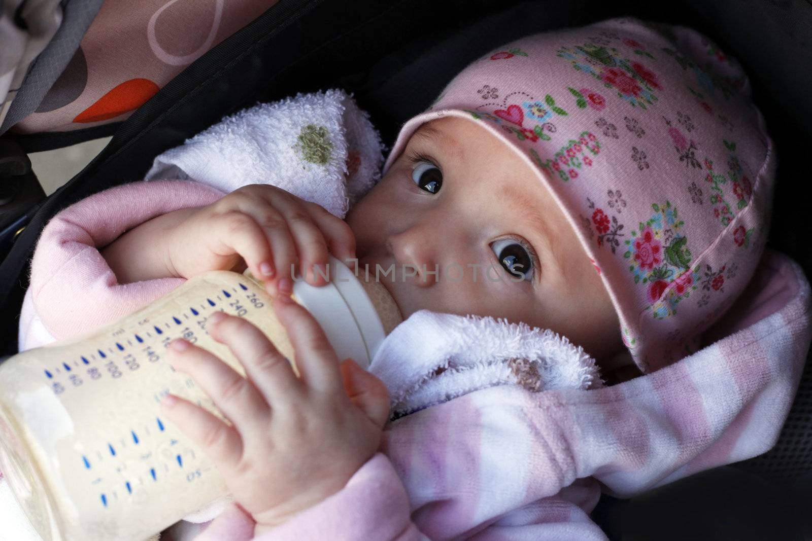 The little girl eats porridge from a bottle