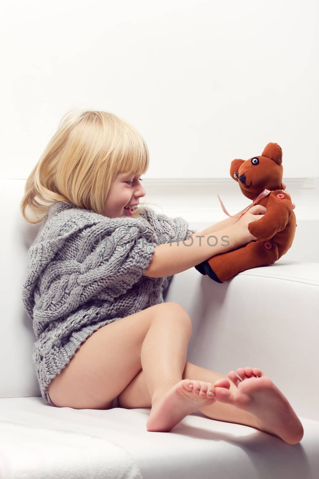 Little girl with bear on white sofa