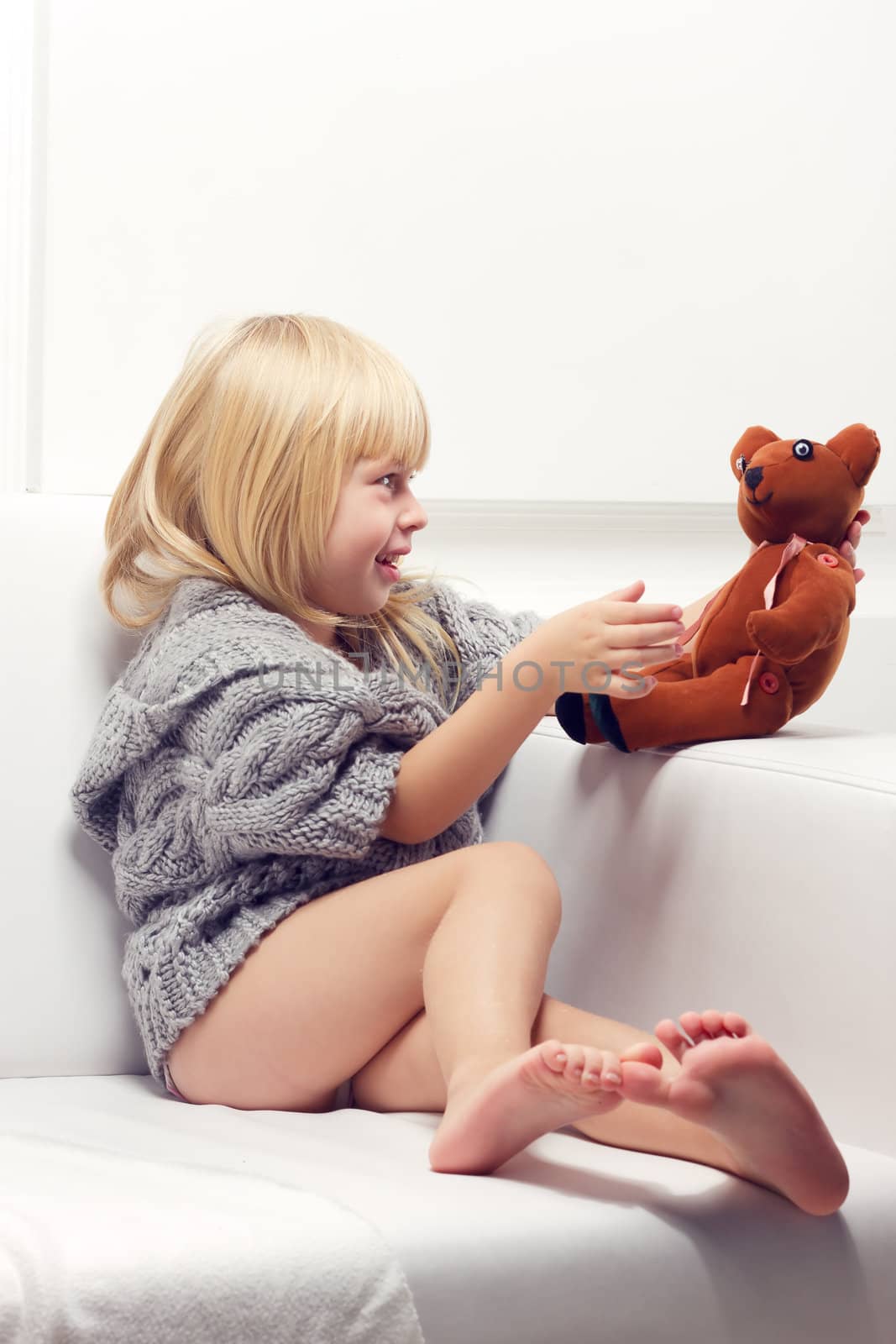 Little girl with bear on white sofa