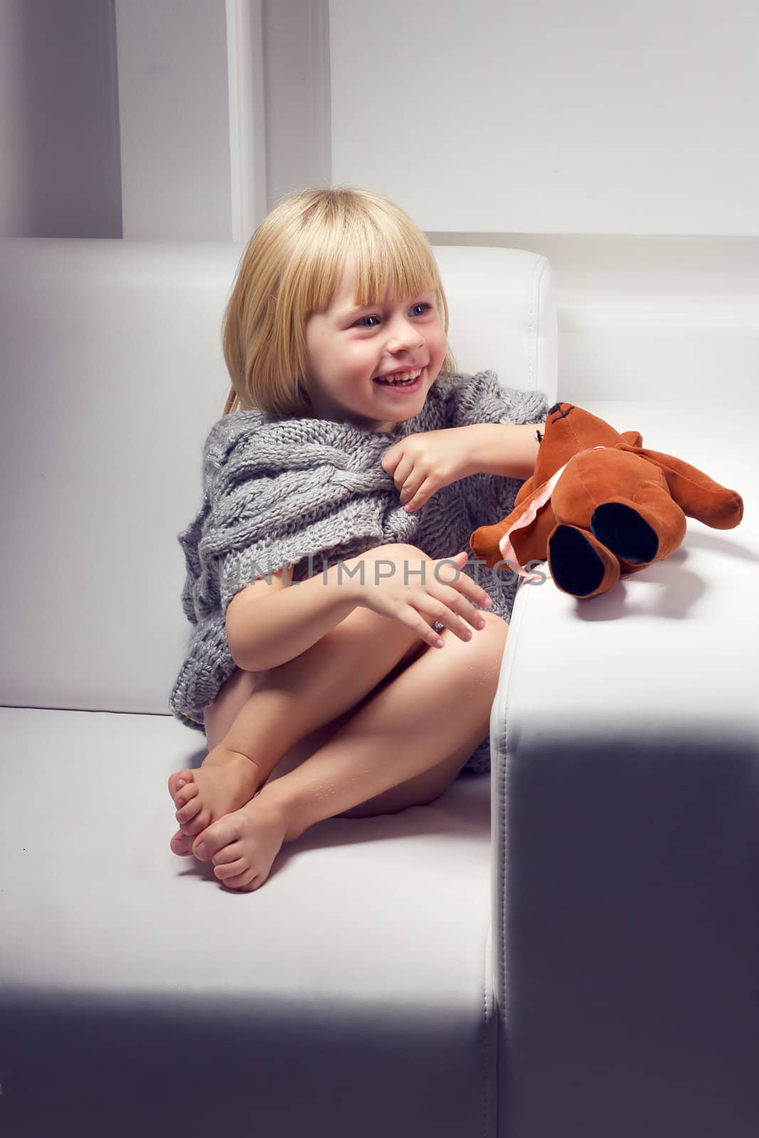 Little girl with bear on white sofa