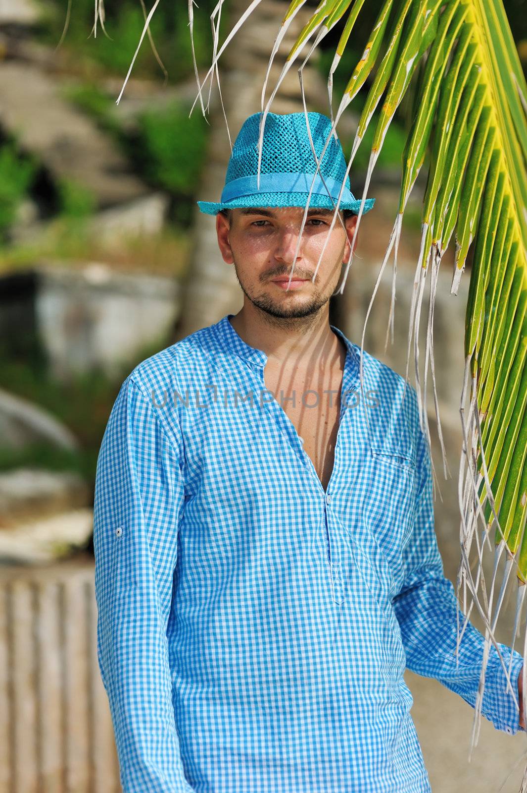 Man in blue hat near palm tree