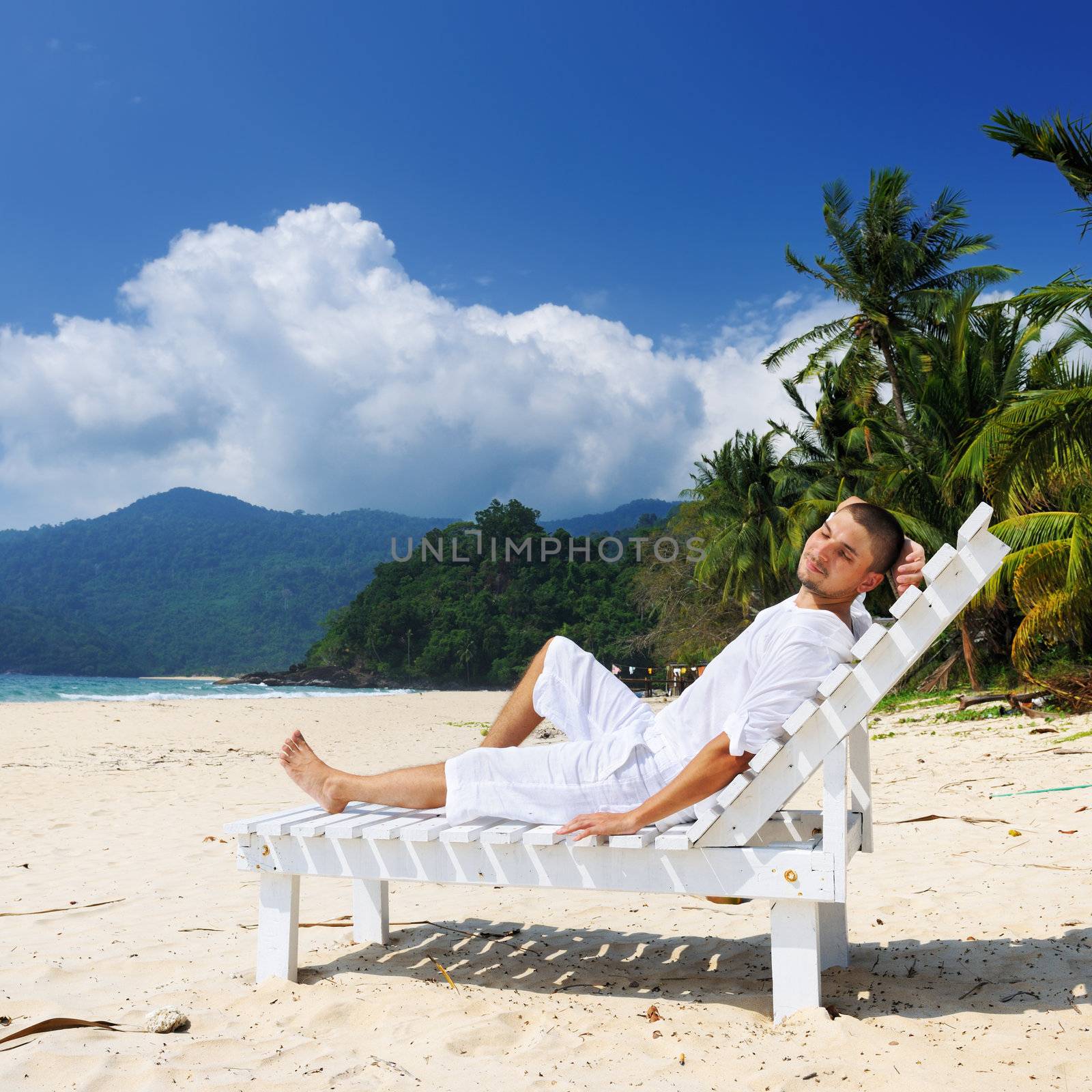 Man in white relaxing on a tropical beach