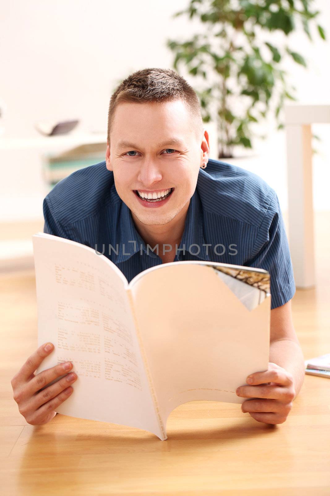 Young man reading magazine at home by rufatjumali