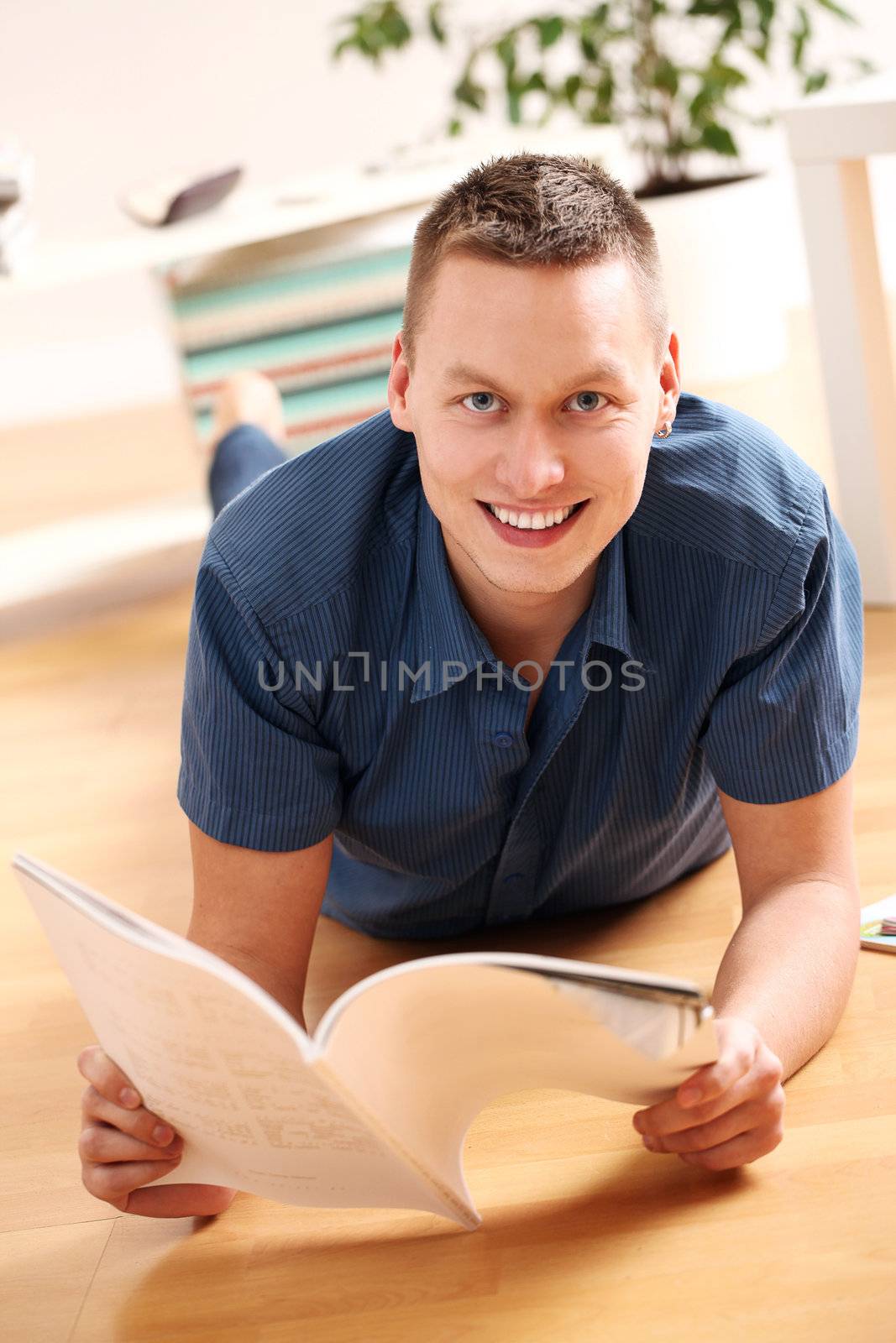 Portrait of Young man reading magazine at home