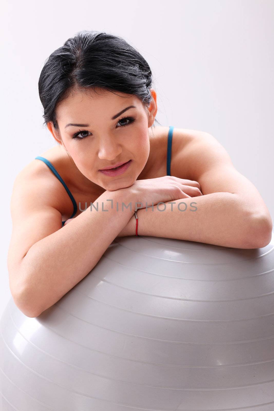 Cute young fitness girl with abs ball in studio