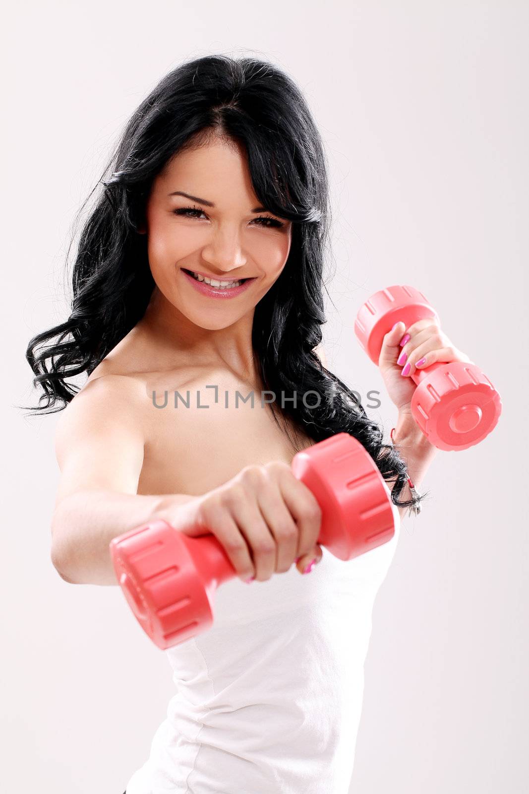 Cute and young girl do exercises with red dumbbells