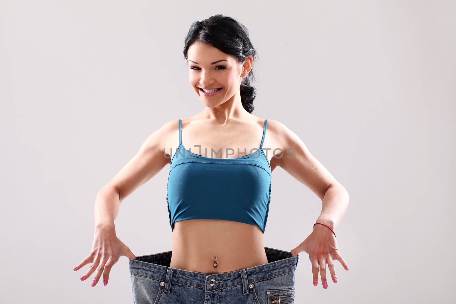 Cute slim girl wearing old jeans after weight loss in studio