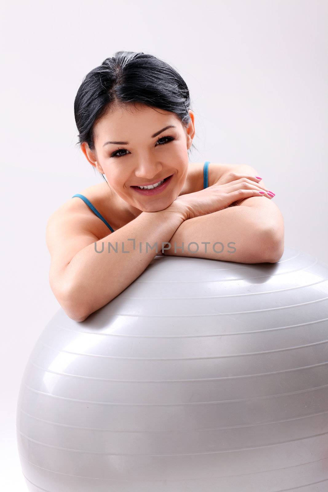 Cute and young fitness girl with abs ball in studio