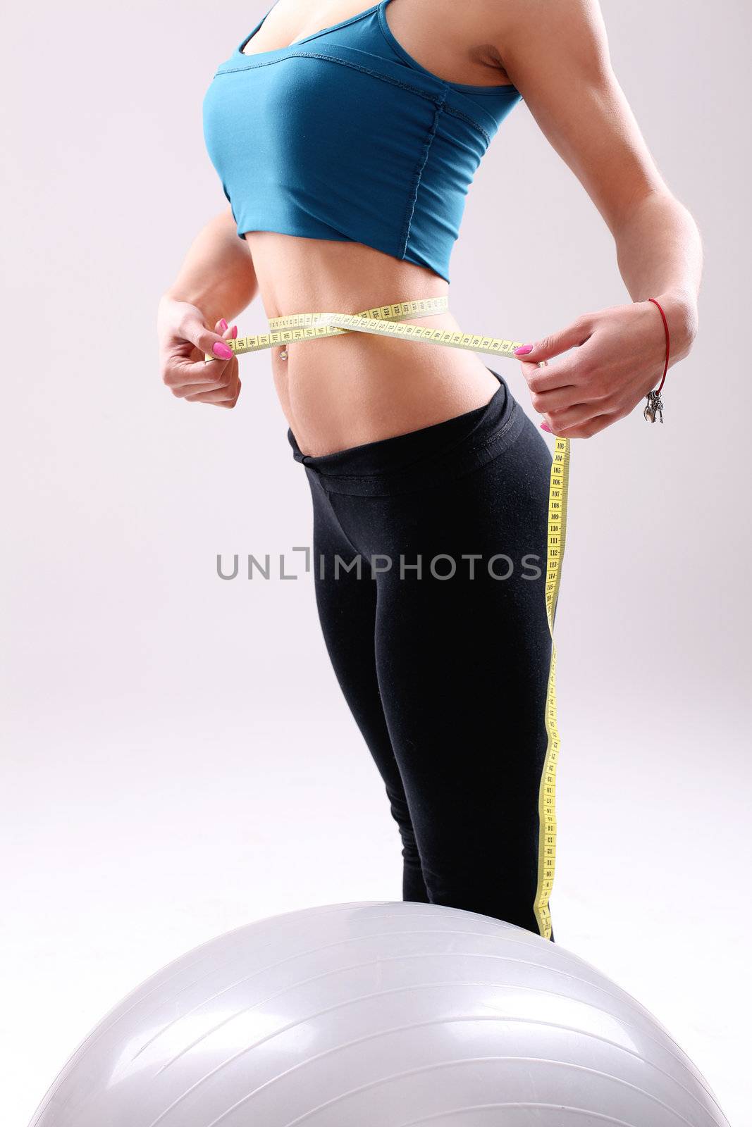 Slim girl measuring her waist with ruler after abs