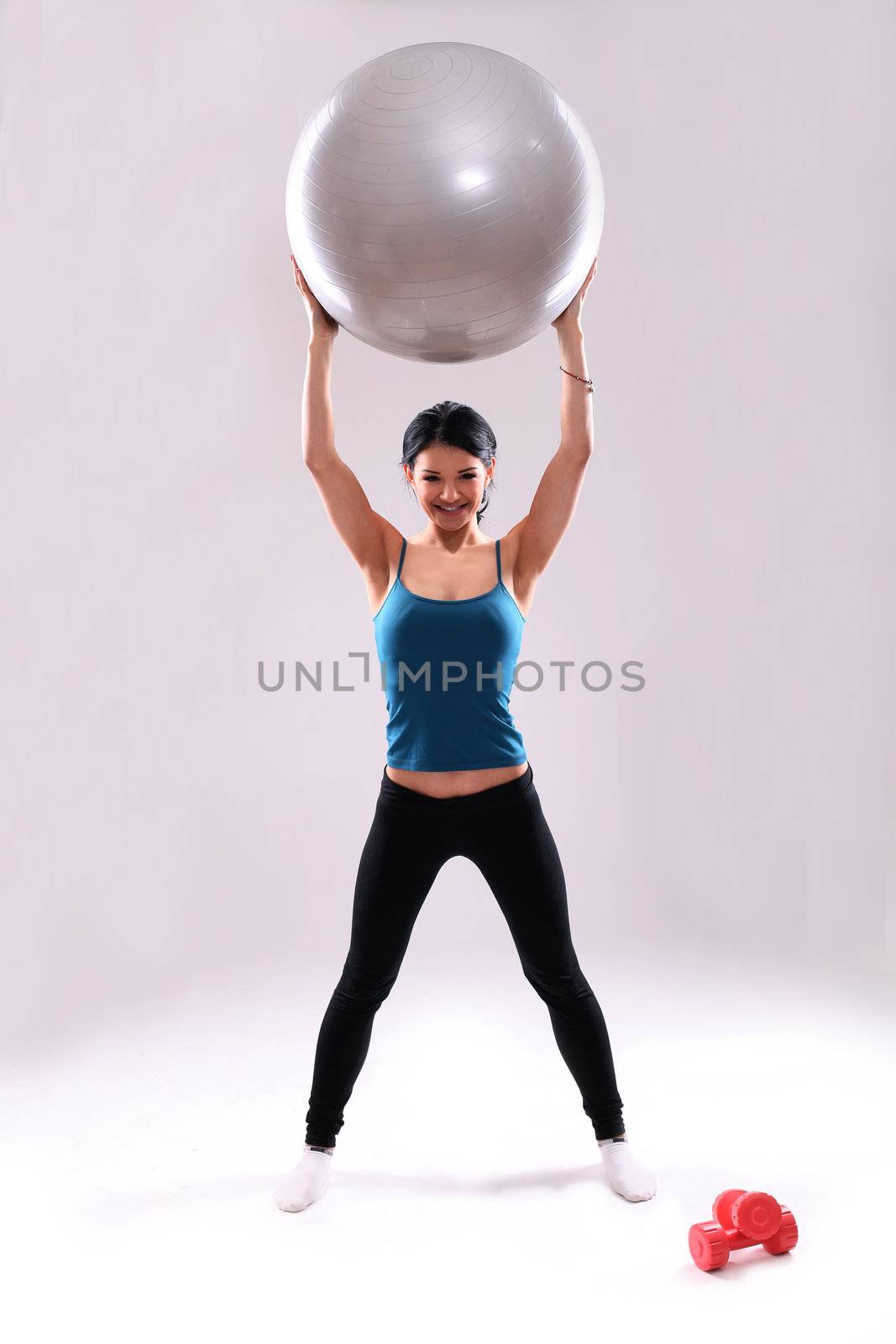 Cute and young fitness girl with abs ball in studio