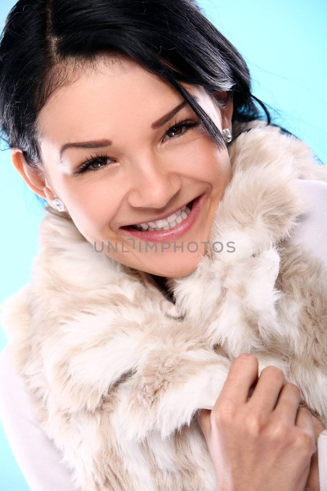 Beautifull smiling young girl in fur isolated on a blue