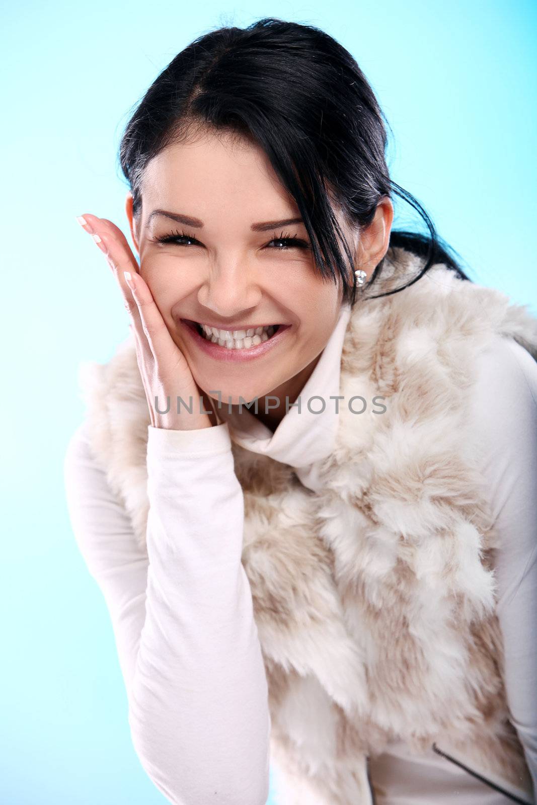 Beautifull smiling young girl in fur isolated on a blue