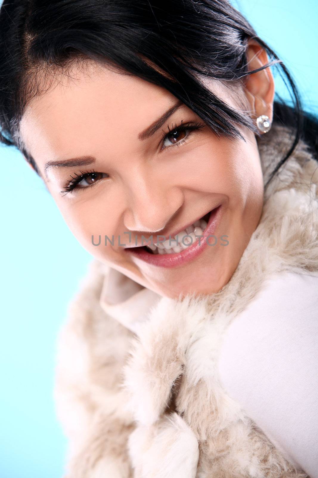 Beautifull smiling young girl in fur isolated on a blue