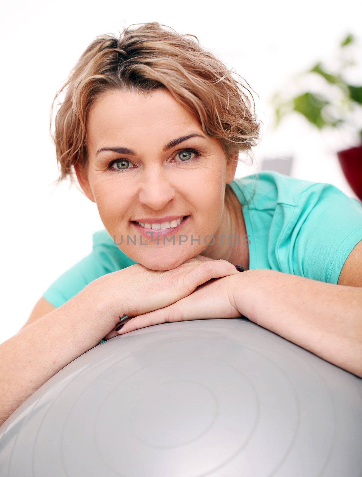 Cute and smiling middle aged woman with abs ball at home