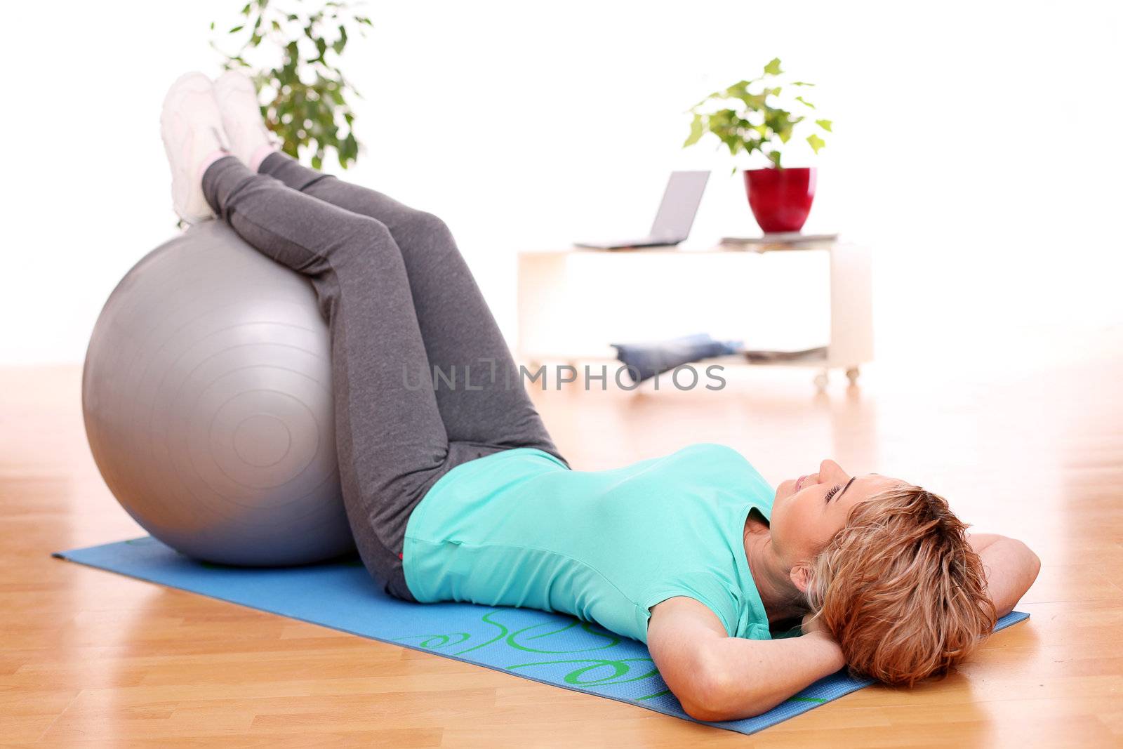 slim mid aged woman do her exercises with abs ball at home