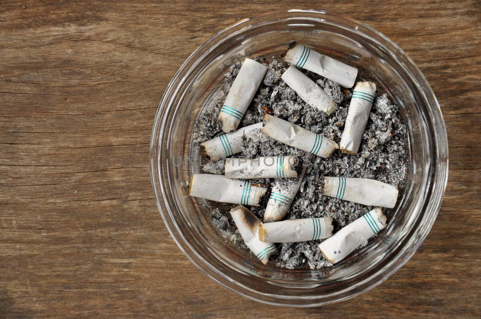 Cigarette butts in a glass ashtray.