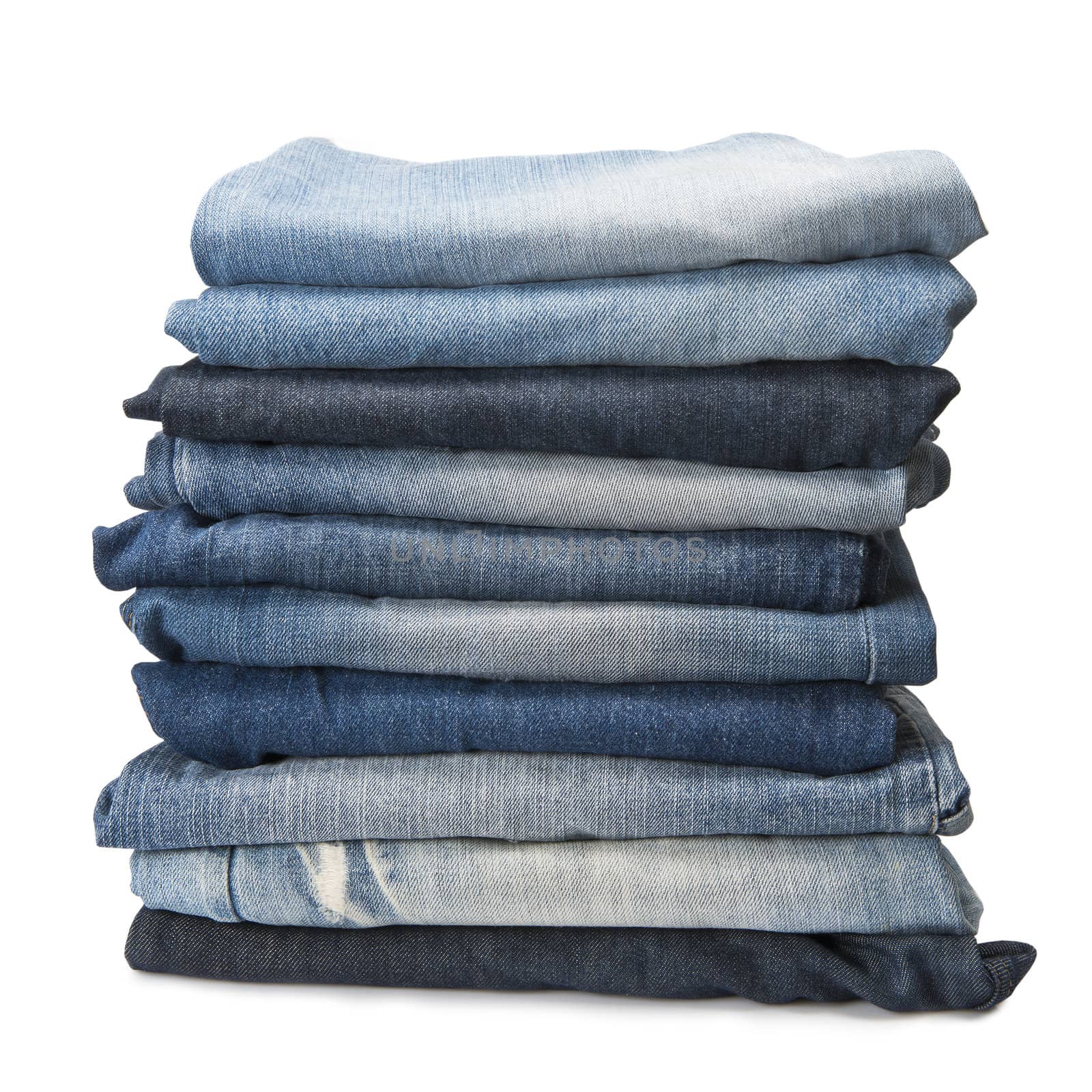 Stack of old and worn blue jeans over a white background
