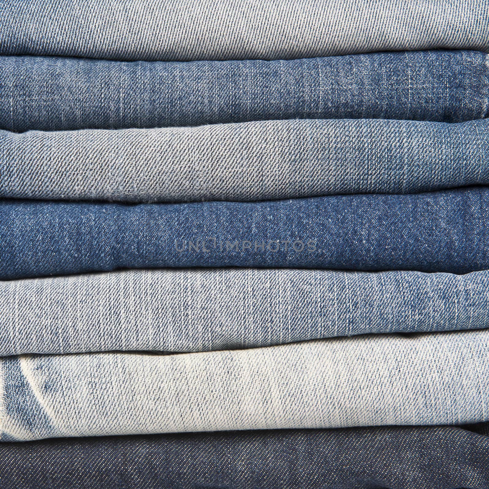 Stack of different old worn blue jeans by angelsimon