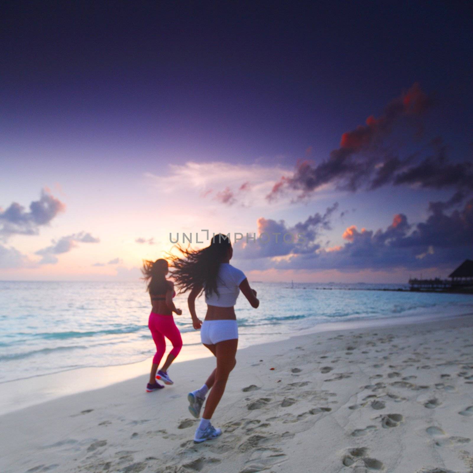 Fitness sport women running on beach at sunset