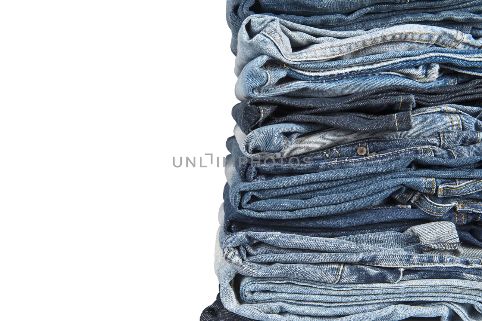 Stack of old and worn blue jeans over a white background