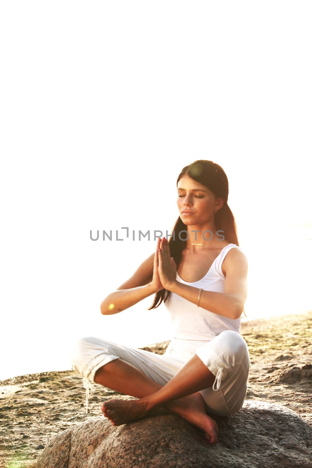 Young woman practicing yoga  near the ocean