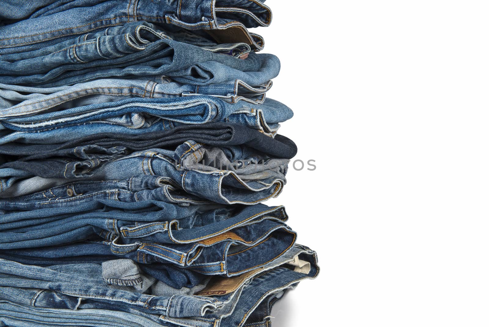 Stack of old and worn blue jeans over a white background