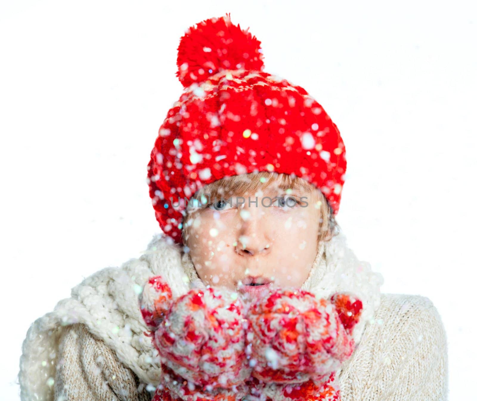 Portrait of young smiling cute teenager in a red hat and mittens with snow, isolated on white