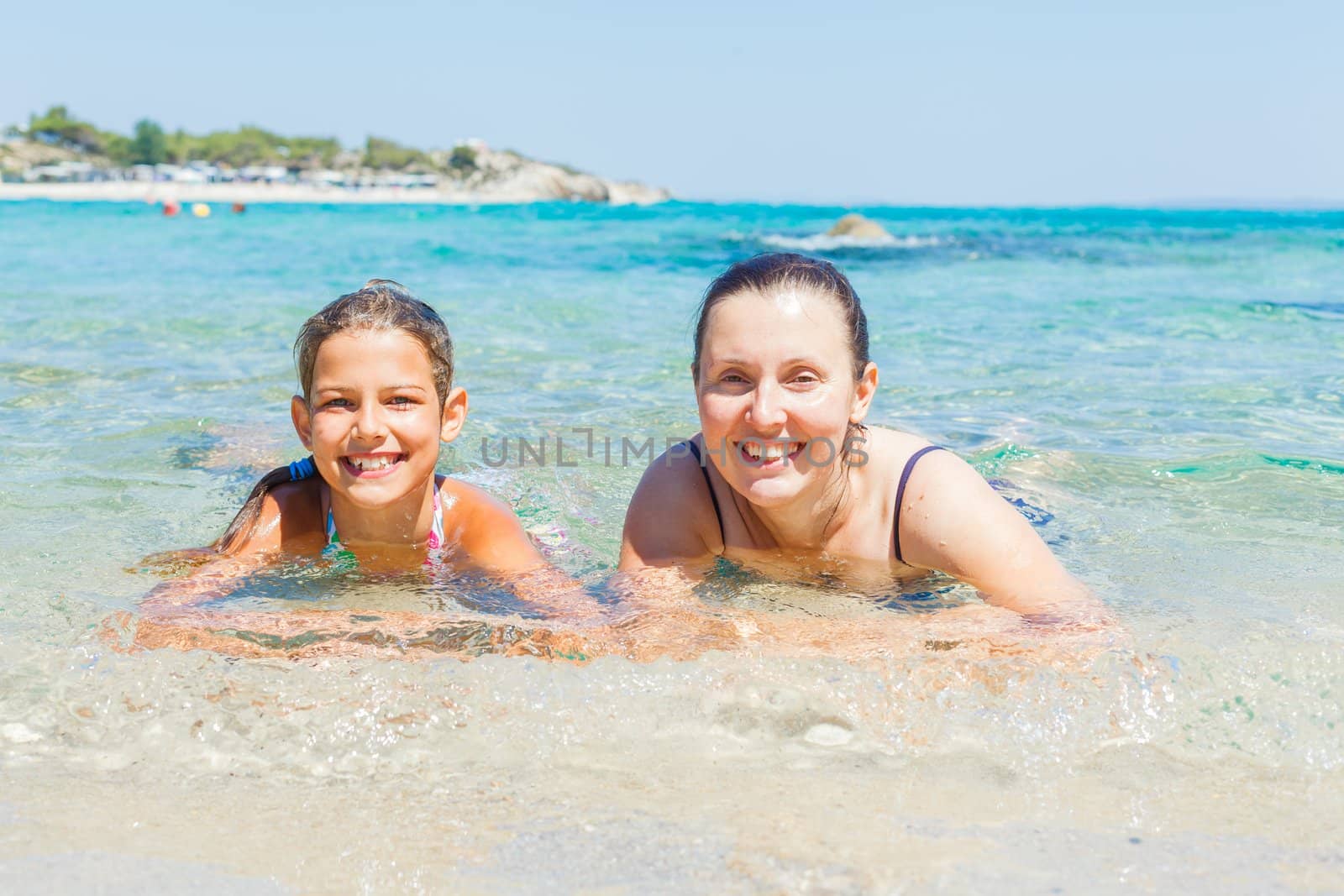 Summer vacation - Mother and cute daughter playing and swimming in the transparent sea