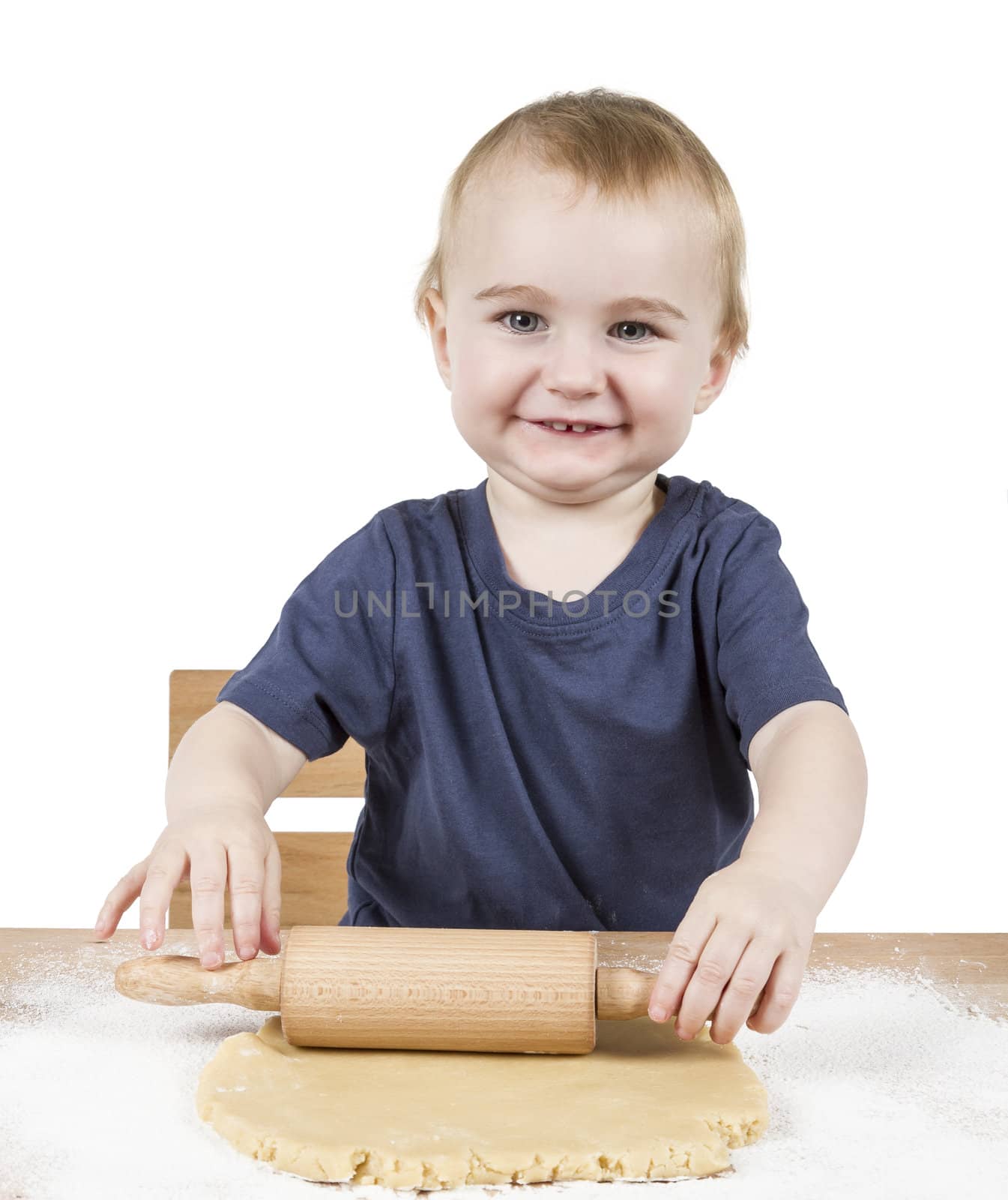 young child making cookies on small wooden desk