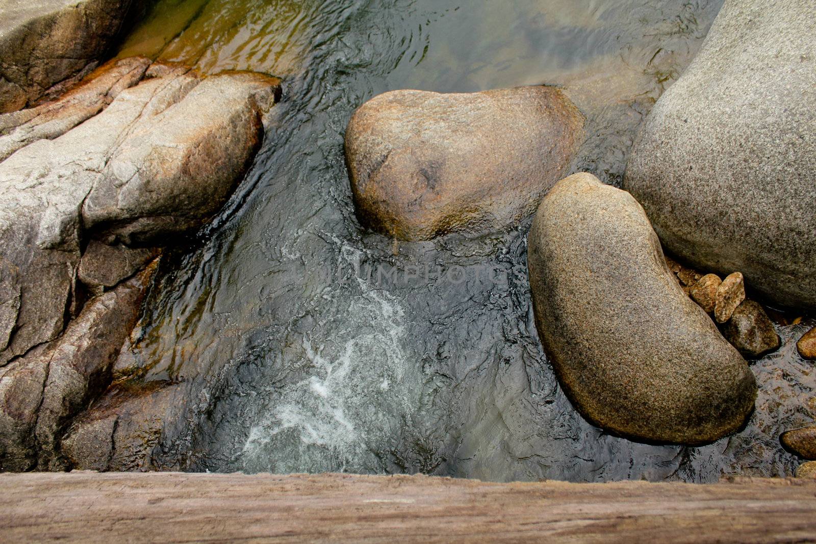 Path made from big log across pond at waterfall