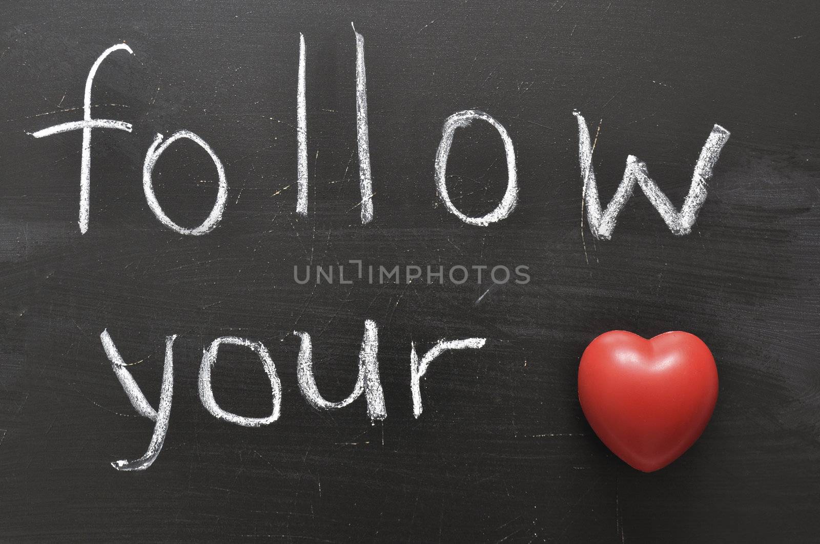 hand written follow your with red heart symbol on black chalkboard