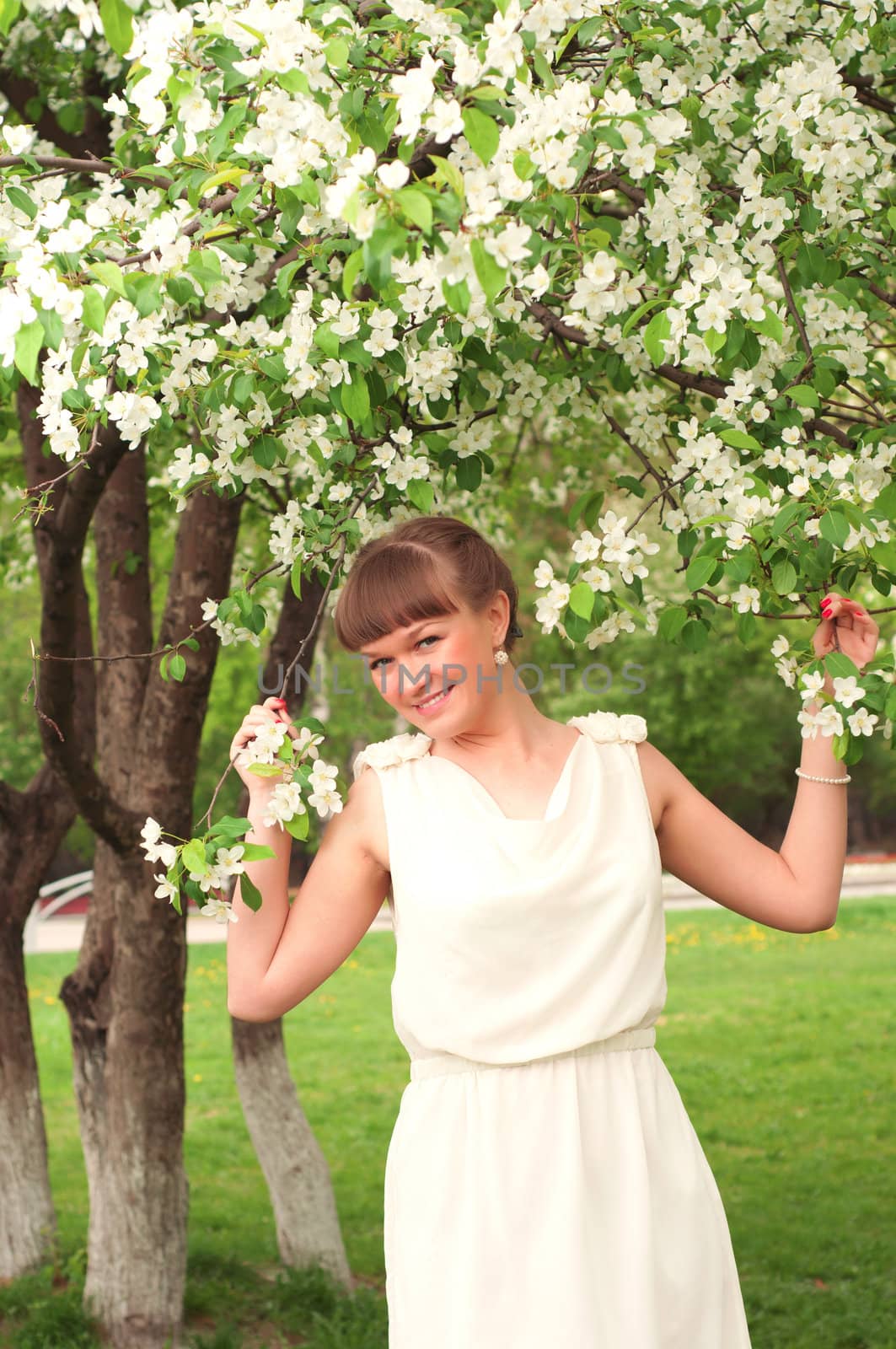 beautiful young brunette woman with the apple tree on a warm summer day