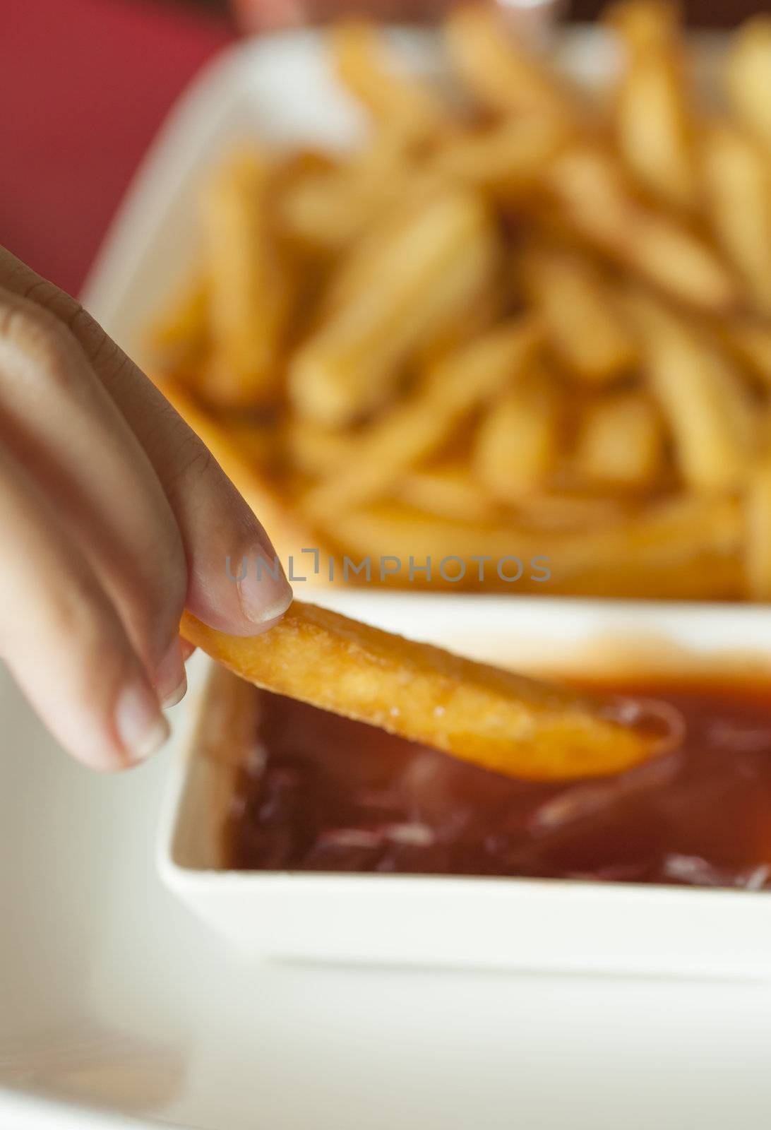 Woman Hand dipping French Fries with Barbecue dip