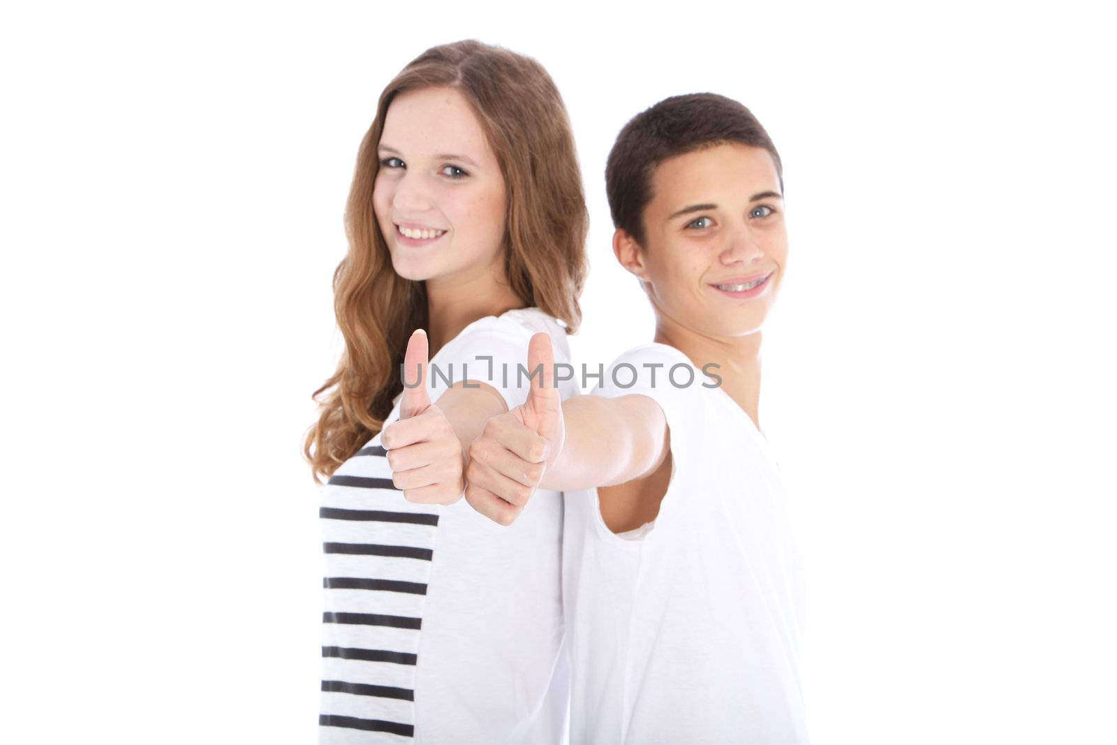 Happy teenage brother and sister standing back to back giving a thumbs up gesture of approval isolated on white